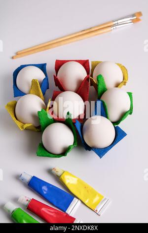 photo paint tube , brushes and eggs in colored packages on white package Stock Photo