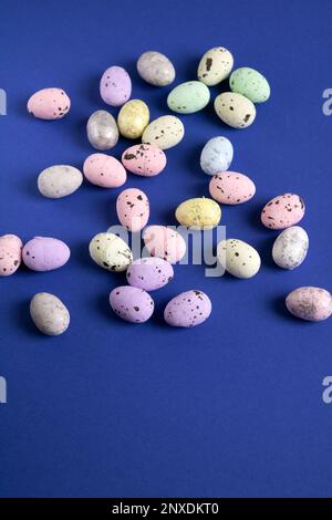 photo of different colored foam quail eggs on a blue background Stock Photo