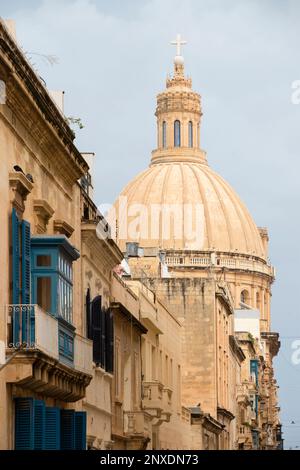 Valletta, Malta - November 12, 2022: Residential stone building facades and the dome of the Basilica of Our Lady of Mount Carmel in Malta's capital Stock Photo