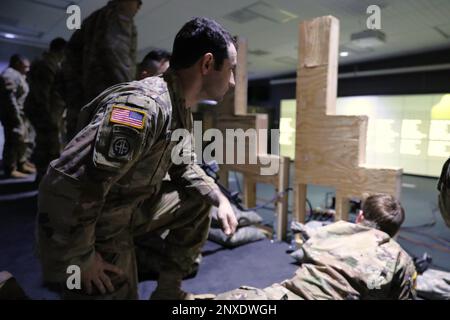 U.S. Army Staff Sgt. Chase McKissick, an infantryman with Charlie Company, 1st Battalion, 112th Infantry Regiment, 56th Stryker Brigade Combat Team, 28th Infantry Division coaches Soldiers at an Engagement Skills Trainer at Fort Indiantown Gap, Pa. February 4, 2023.      “It is a good beginning testing block for our company. Training this way allows us to perfect our fundamentals without being in a rough environment,” said McKissick.    The EST is also a great opportunity for Soldiers to hone their skills without expending live ammunition.     “Our Soldiers can understand the format of how the Stock Photo