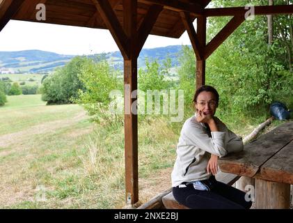 A hiker rests his head and rests in a wooden shelter during a hike Stock Photo