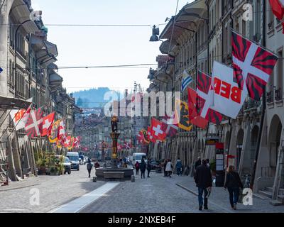 Berne, Switzerland - April 16th 2023: View along the main street decorated with flags in the historic city centre Stock Photo