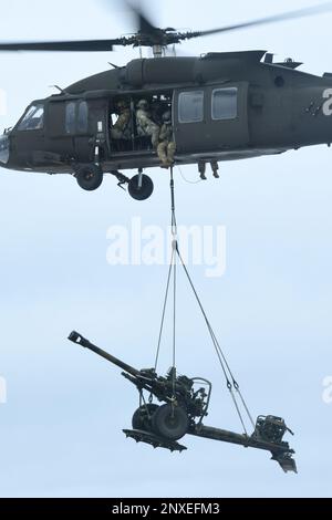 A UH-60 Blackhawk from the 1-147th Aviation Regiment, Michigan National Guard, lifts a M119 howitzer from the 1-120th Field Artillery Regiment, Wisconsin National Guard, while conducting a sling load during Northern Strike 23-1, Jan. 23, 2023, at Grayling Army Airfield, Mich. Northern Strike’s winter iteration serves as a cost effective way for units across the Department of Defense to conduct cold-weather, joint all-domain operations. Stock Photo