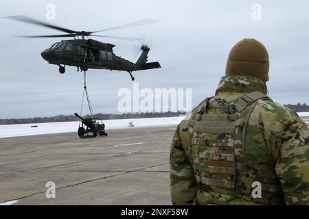 A UH-60 Blackhawk from the 1-147th Aviation Regiment, Michigan National Guard, lifts a M119 howitzer from the 1-120th Field Artillery Regiment, Wisconsin National Guard, while conducting a sling load during Northern Strike 23-1, Jan. 23, 2023, at Grayling Army Airfield, Mich. Northern Strike’s winter iteration serves as a cost effective way for units across the Department of Defense to conduct cold-weather, joint all-domain operations. Stock Photo