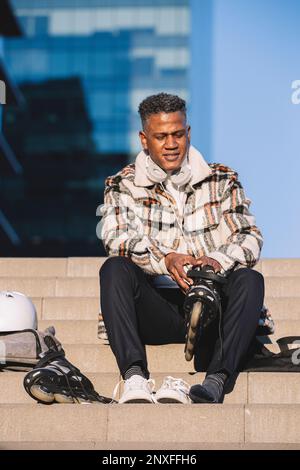 Man putting on his inline skates while sitting on a stair in a city park Stock Photo