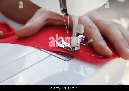 Tailor sews clothes on electrc sewing machine in close up, focus on needle. Stock Photo