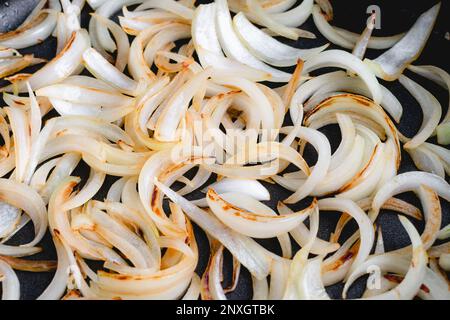 Close Up View of Sliced Onions Browned in a Skillet: Slices of sweet onion cooked in olive oil browning in a frypan Stock Photo