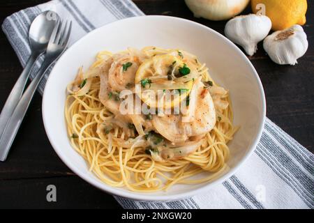 Chicken Piccata Served Over Spaghetti in a Pasta Bowl: Chicken, onions, and lemons in sauce made of garlic and white wine Stock Photo