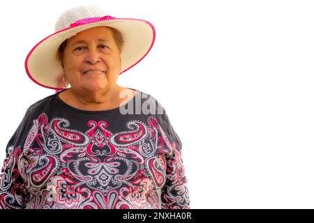 Beautiful smiling elderly woman with short hair, wearing a hat and a black blouse with pink trimmings against white background, looking at camera, enj Stock Photo