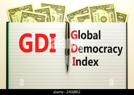 GDI global democracy index symbol. Concept words GDI global democracy index on white note on beautiful background from dollar bills. Pen. Business and Stock Photo