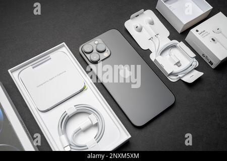 New iPhone 14 pro max and Apple Earpods, Airpods white earphones for listening to music and podcasts in an open box. Isolated black background. Stock Photo