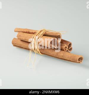 Bunch of cinnamon sticks on a light background with reflection in a glass background. Stock Photo