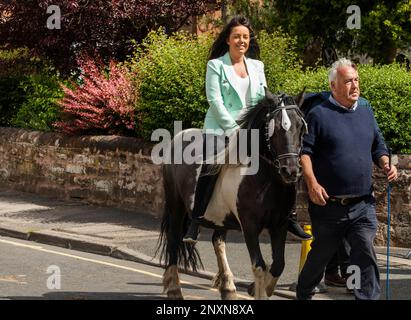 Pretty woman looking happy with long dark hair riding bareback on small brown and white horse  Appleby Horse Fair Appleby in Westmorland  Cumbria Stock Photo