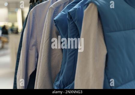 Sleeveless shirts and jackets hang on hangers in the store. Stock Photo