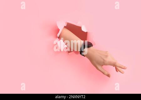 Female hand and smartwatch visible through torn pink paper Stock Photo ...