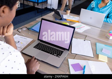Diverse businesswomen using laptops, one with copy space on screen, at office Stock Photo
