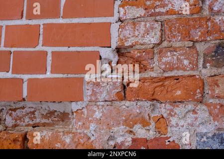 A fragment of an old red brick wall. Wall restoration site with new bricks. Stock Photo