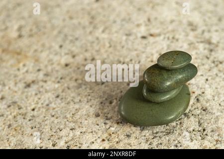 smooth stacked little jade pebbles stacked up on a much larger light granite cobble Stock Photo