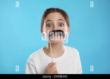Cute little girl with fake mustache on turquoise background Stock Photo