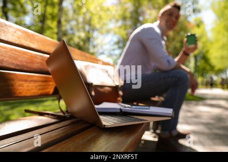 Man taking coffee break during work in park, focus on laptop Stock Photo