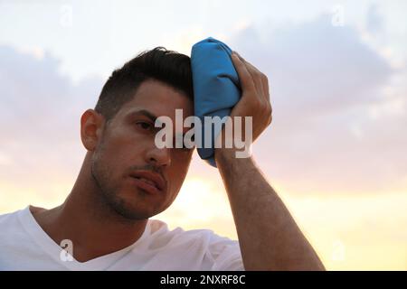 Man with cold pack suffering from heat stroke outdoors at sunset Stock Photo