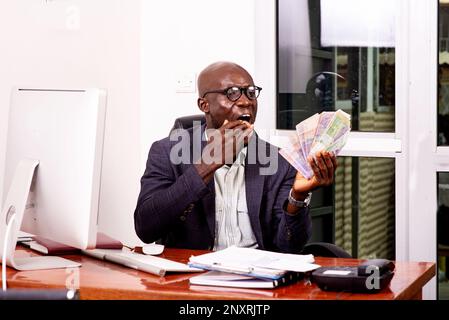 portrait of a businessman sitting and counting money bills in the office. Stock Photo