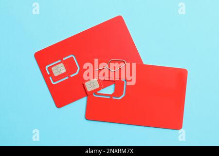 Red SIM cards on light blue background, flat lay Stock Photo