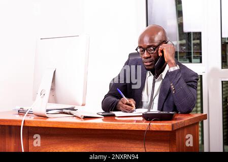 portrait of an adult business man talking on mobile phone and taking notes in the notebook in the office. Stock Photo