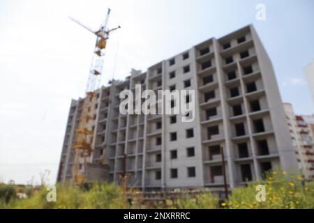 Blurred view of unfinished building and construction crane outdoors Stock Photo