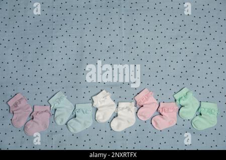 Many colorful baby socks on light blue fabric, flat lay. Space for text Stock Photo