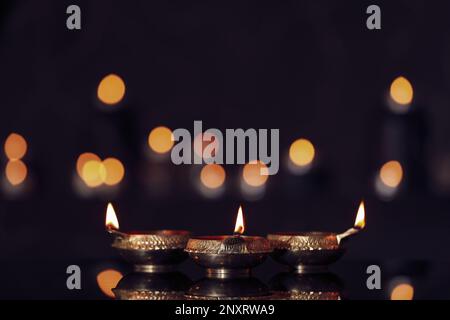 Lit diyas on table against blurred lights. Diwali lamps Stock Photo