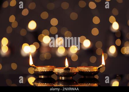 Lit diyas on table against blurred lights. Diwali lamps Stock Photo