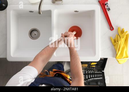 Plumber using plunger to unclog sink drain, top view Stock Photo