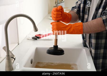 https://l450v.alamy.com/450v/2nxta96/man-using-plunger-to-unclog-sink-drain-in-kitchen-closeup-2nxta96.jpg