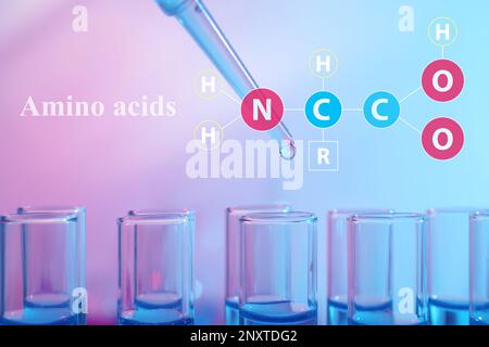 Amino Acids chemical formula, illustration. Dripping reagent into test tube with blue liquid, closeup Stock Photo