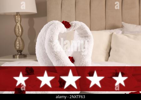 Five Star Luxury Hotel. Beautiful swans made of towels decorated with red roses on bed in five star hotel room Stock Photo