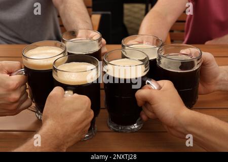 Friends clinking glasses with beer at table, closeup Stock Photo