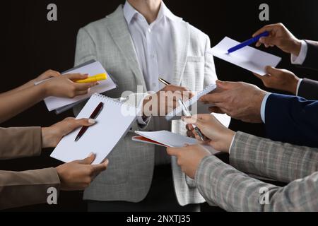 Man signing autograph in notebooks on black background, closeup Stock Photo