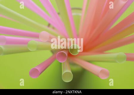 Different plastic straws on green background, above view Stock Photo