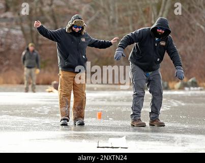 Jason Goldstein, left, and Jon Ross, side across the ice to check the  raised flag on an ice fishing tip-up as a group of co-workers from Noank  Shipyard take advantage of a