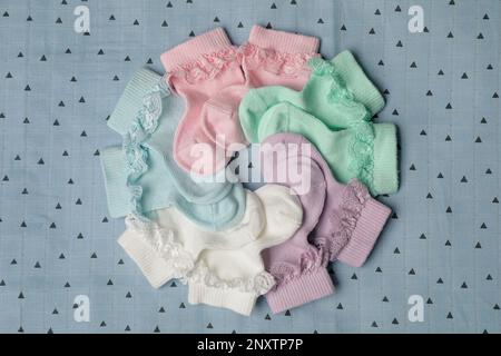 Many colorful baby socks on light blue fabric, flat lay Stock Photo