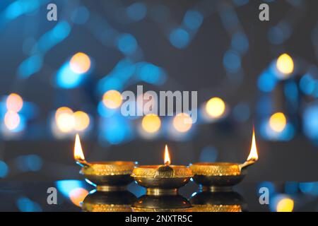 Lit diyas on table against blurred lights. Diwali lamps Stock Photo