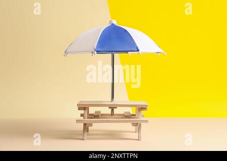 Small wooden holder with toy umbrella on color background Stock Photo