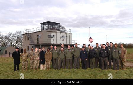 U.S. Air Force Airmen from the 351st Air Refueling Squadron; Rob Paley, 100th Air Refueling Wing historian, and Dr. (Col. ret.) Tom Torkelson, former 100th ARW and 351st ARS commander, gather in front of the air traffic control tower after a patching ceremony at the 100th Bomb Group Memorial Museum, Thorpe Abbotts, England, Feb. 2, 2023. The patching ceremony dates back to World War II and the “Buzzard” patch, presented to pilots and boom operators who have completed mission certification training, is the patch of the 351st Bomb Squadron which flew out of Thorpe Abbotts during World War II. Stock Photo