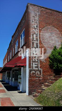 Old sign painted on the King Furniture Company is still visible.  Red brick building has painted company name on front and a furniture sign, and arrow Stock Photo