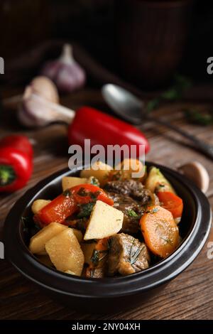 Tasty cooked dish with potatoes in earthenware on wooden table Stock Photo