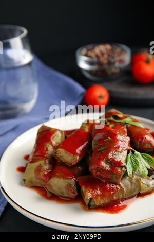 Delicious stuffed grape leaves with tomato sauce on table Stock Photo