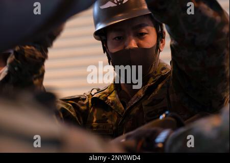Soldiers of Japan's Ground Self-Defense Force hang from a helicopter ...