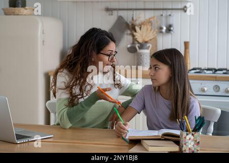 Confused teacher tutor woman in eyeglasses studying with schoolgirl preparing for exam test at home. Stock Photo