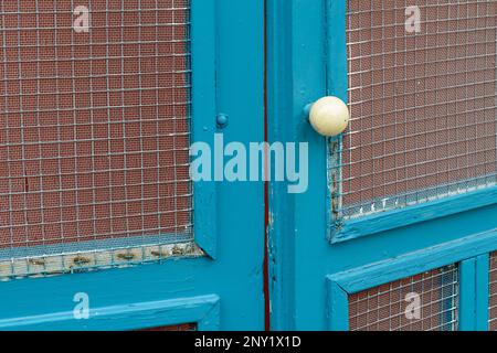 Antique ivory (or porcelain) door knob on an old wooden exterior screen door on February 17, 2023 in New Orleans, Louisiana, USA Stock Photo